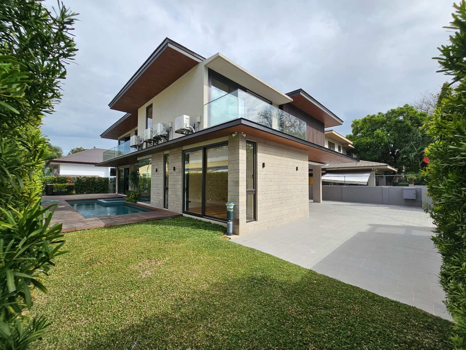 Side garden with manicured lawn, pool and travertine-clad two-storey volume