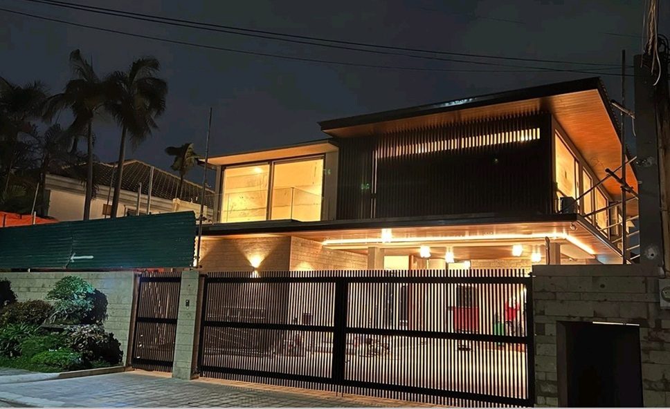 Illuminated facade at dusk behind a black slatted gate in Ayala Alabang Village