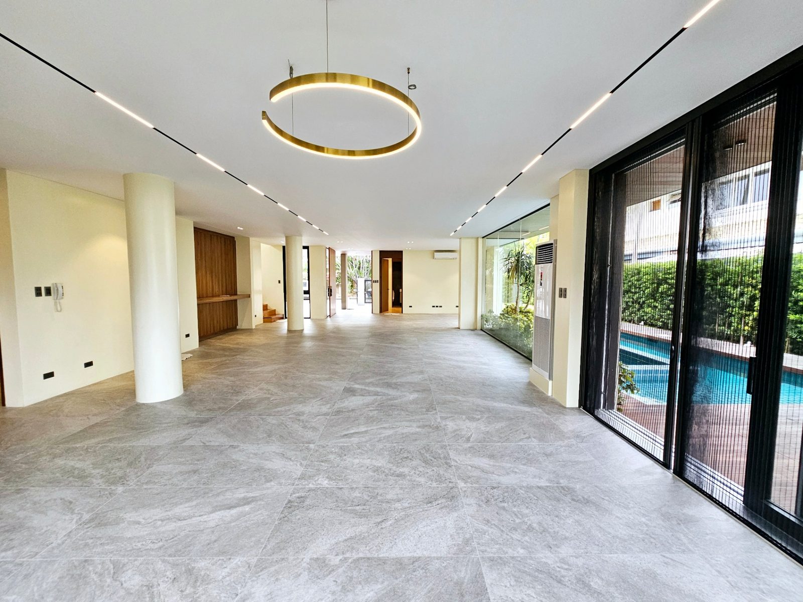 Grand open-plan great room with sculptural brass ring chandelier and pool views