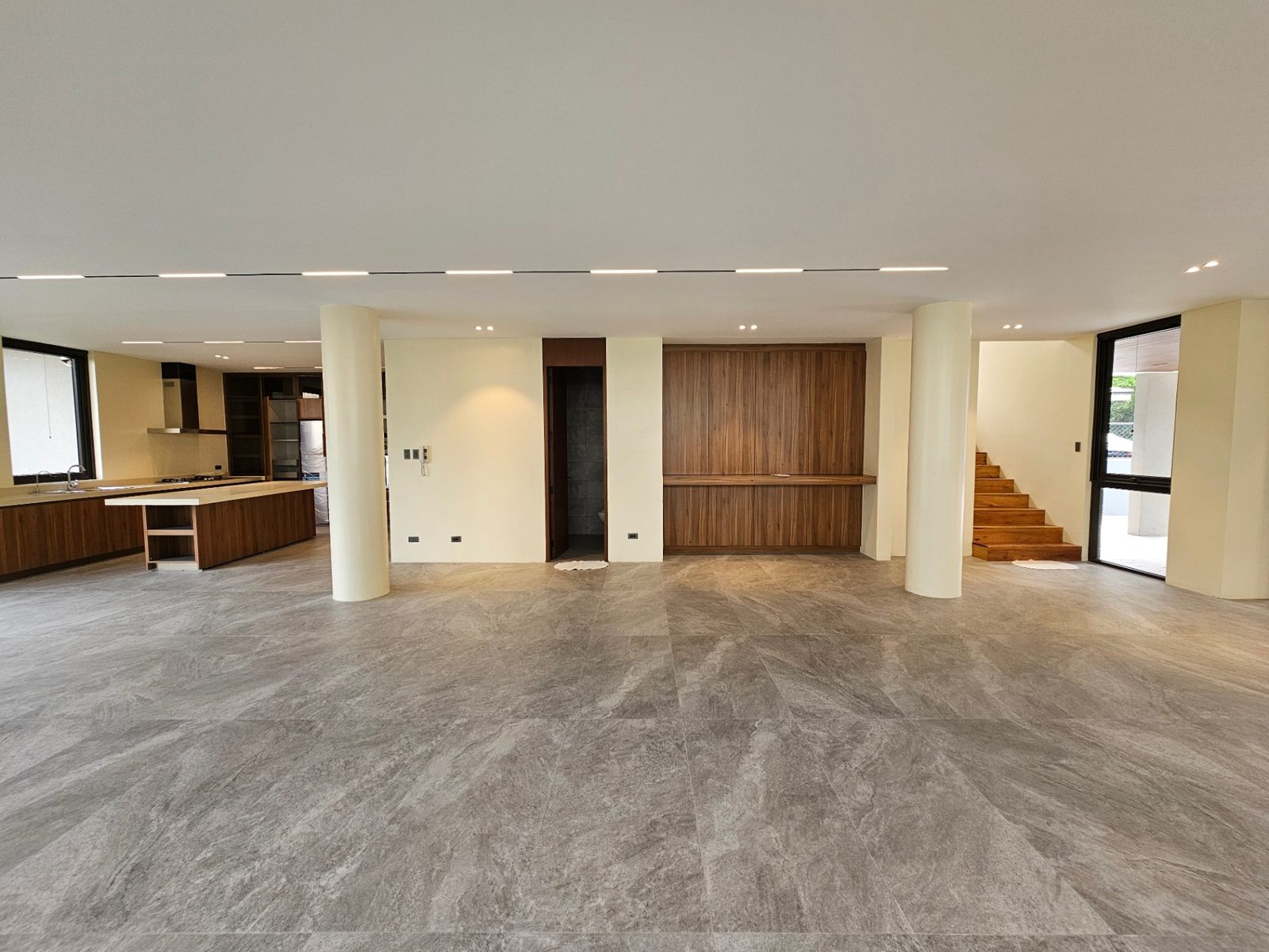 Open living and dining area flowing to the kitchen with walnut feature wall and floating stair