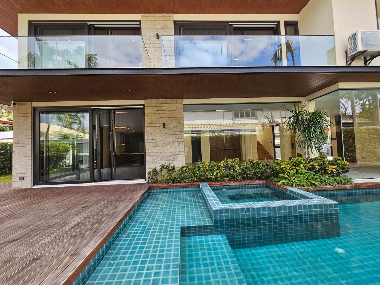 Mosaic-tiled swimming pool with raised spa, timber deck and tropical planting