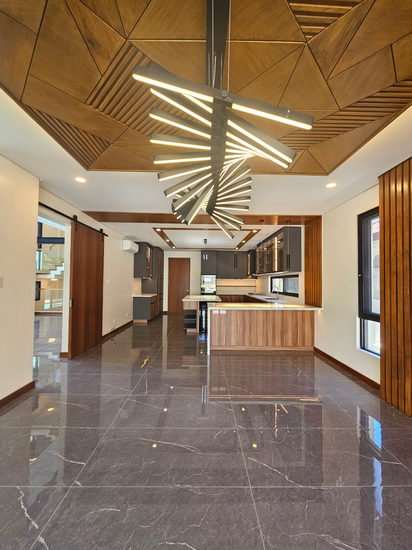 Open-plan dining and kitchen beneath a geometric timber ceiling