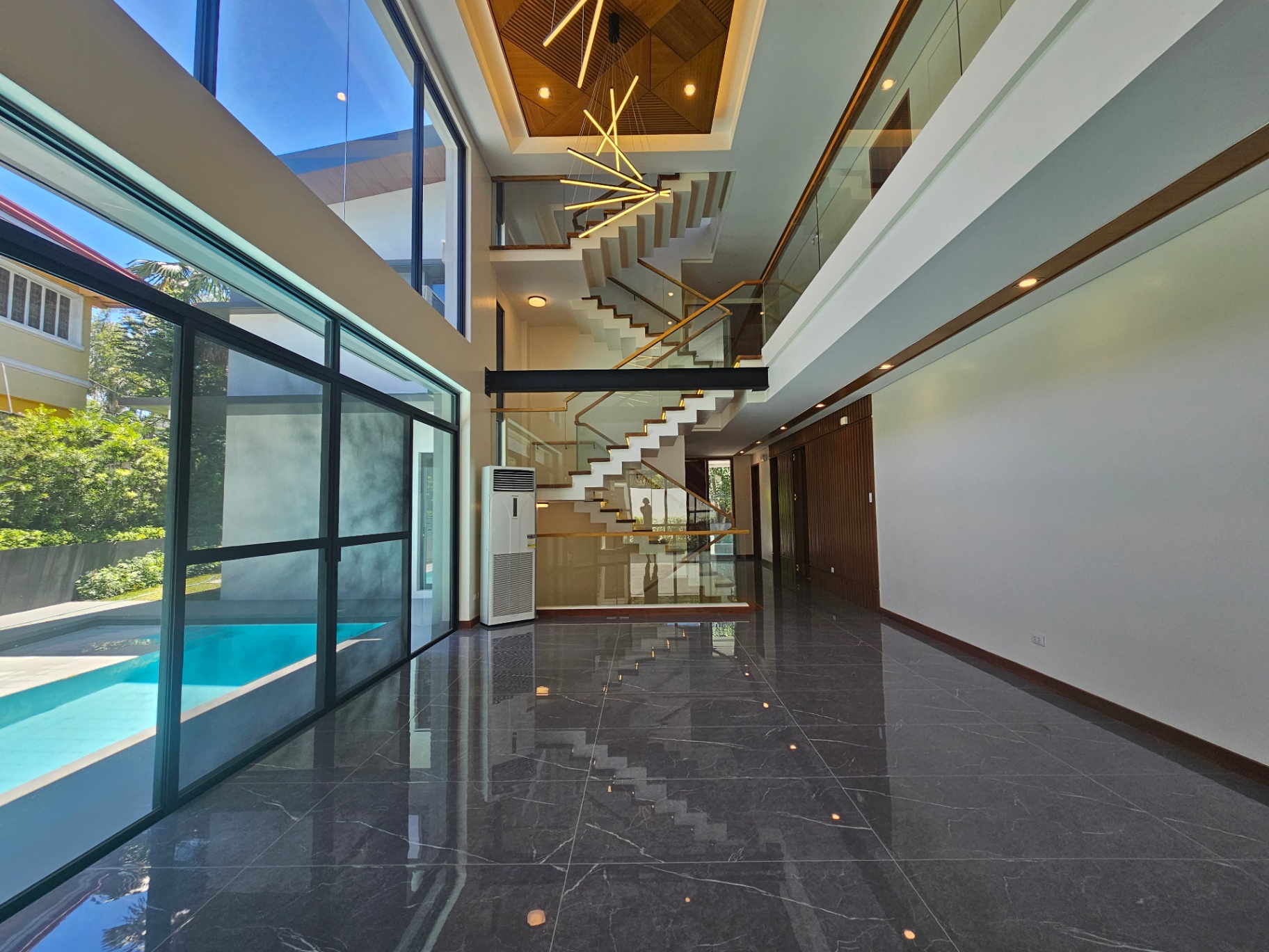 Double-height living hall with floating staircase and pool view