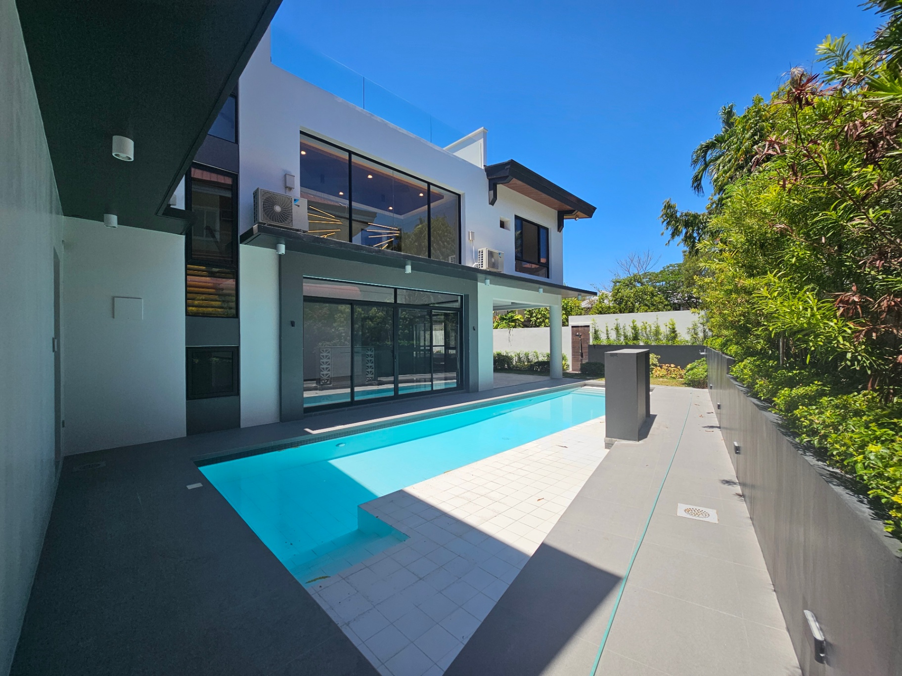 Swimming pool with water feature beside the glass-walled residence
