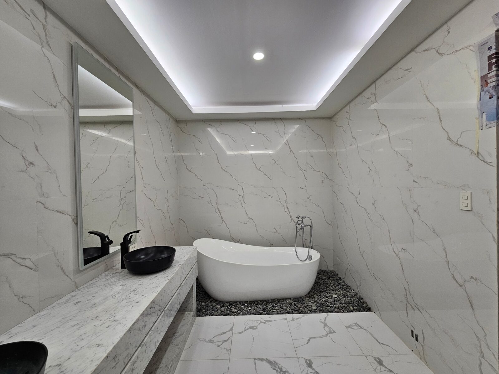 Marble bathroom with freestanding soaking tub on pebble bed