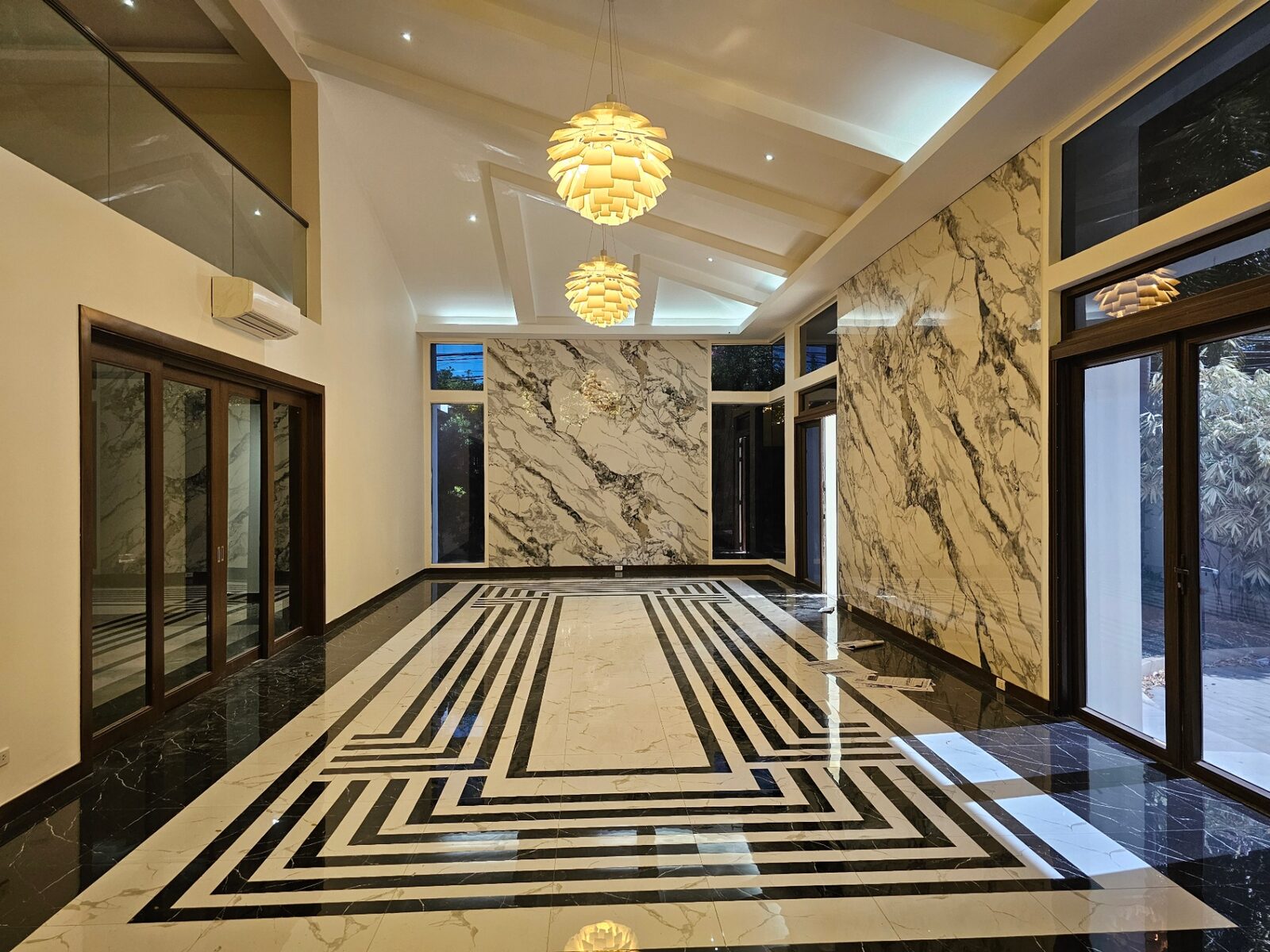 Grand foyer with cathedral ceiling, marble walls and patterned marble floor