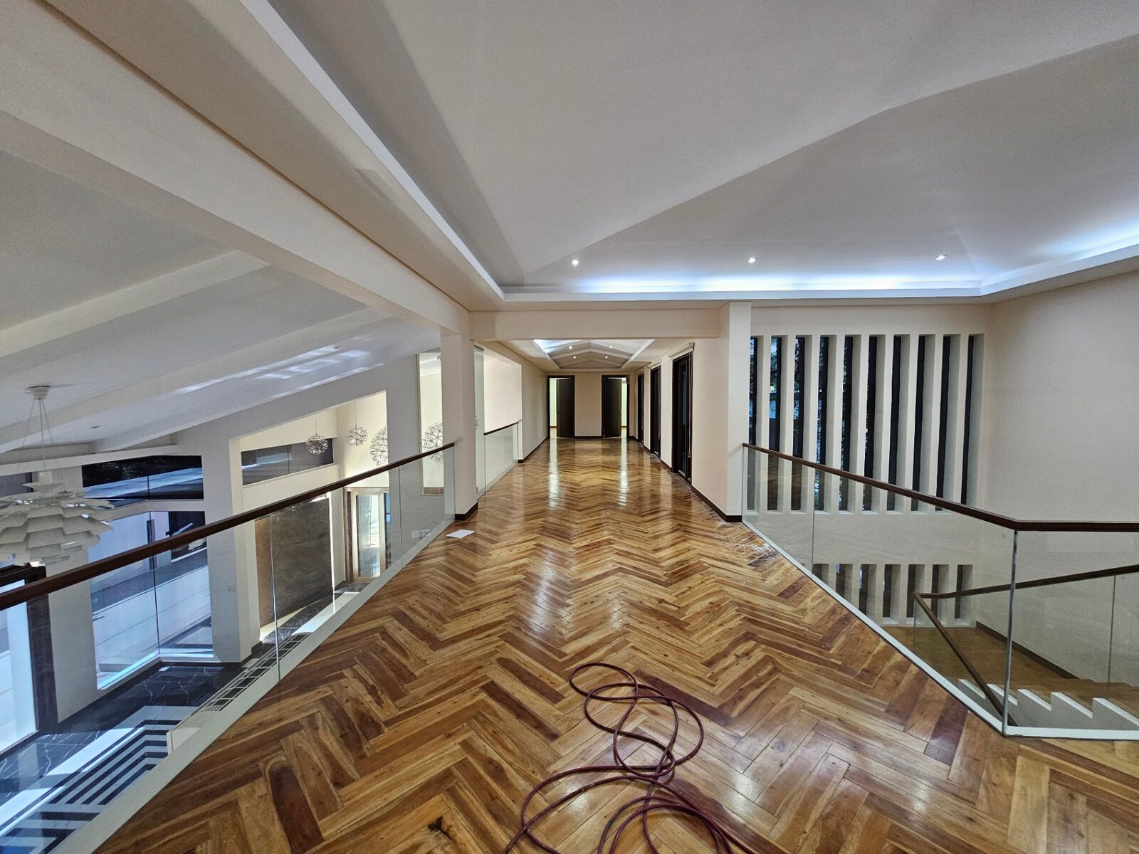 Upper-floor gallery hall with herringbone wood floors overlooking the void