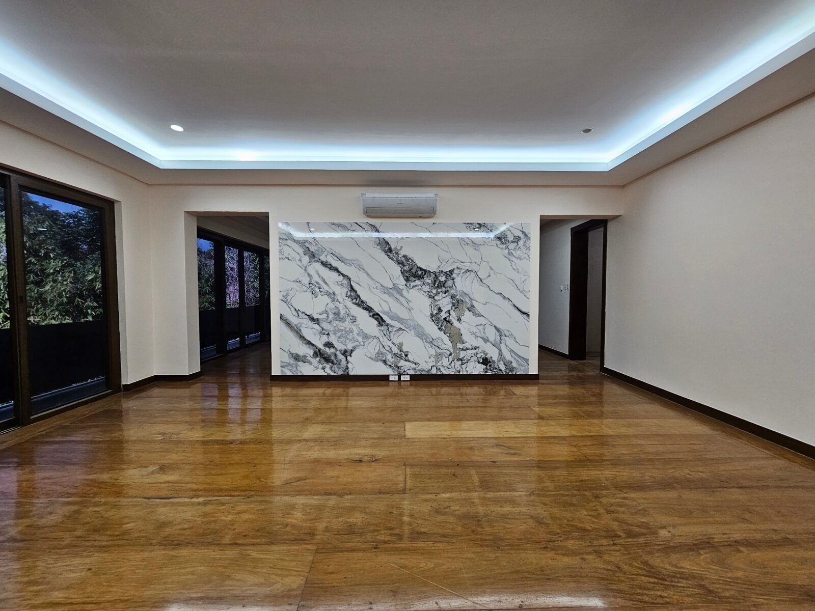 Spacious lounge with hardwood floors and dramatic marble feature wall