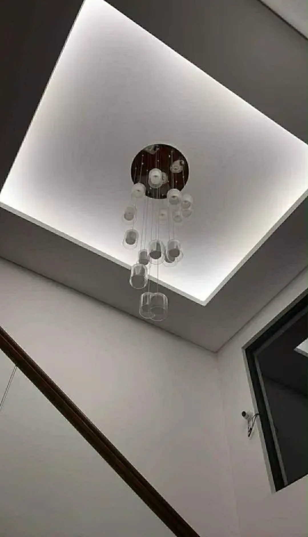 Double-height atrium with cove lighting and pendant chandelier