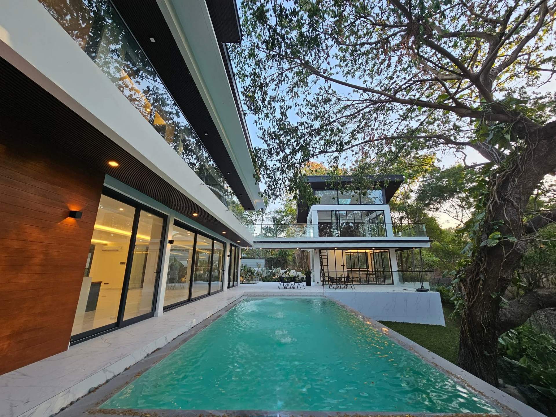 Infinity pool framed by mature trees and the cabana beyond