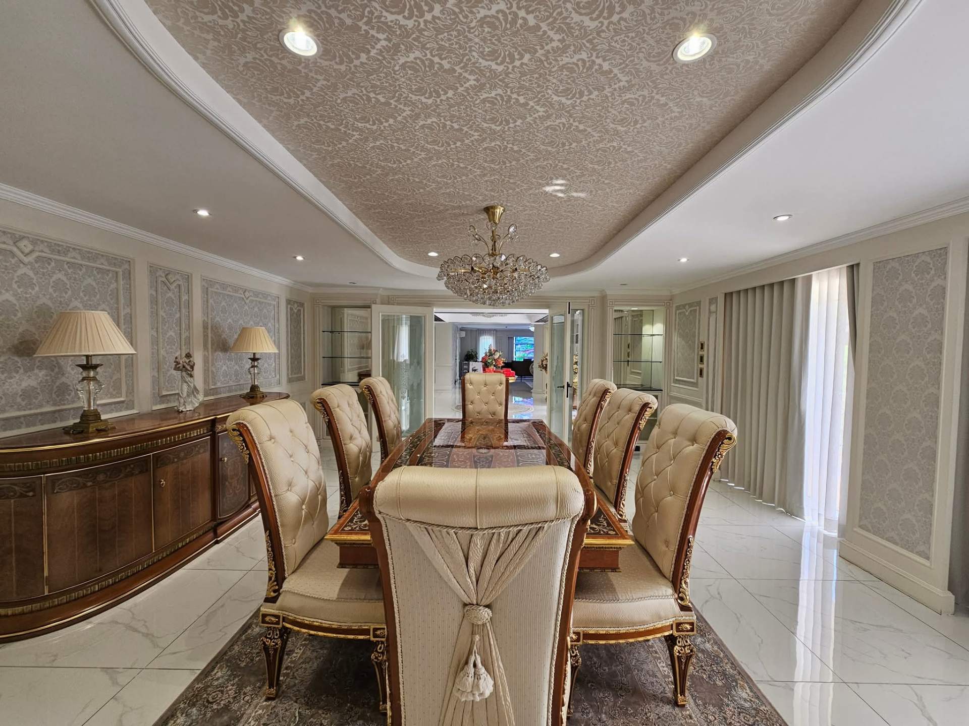 Formal dining room seating eight with damask wallpaper and marble flooring