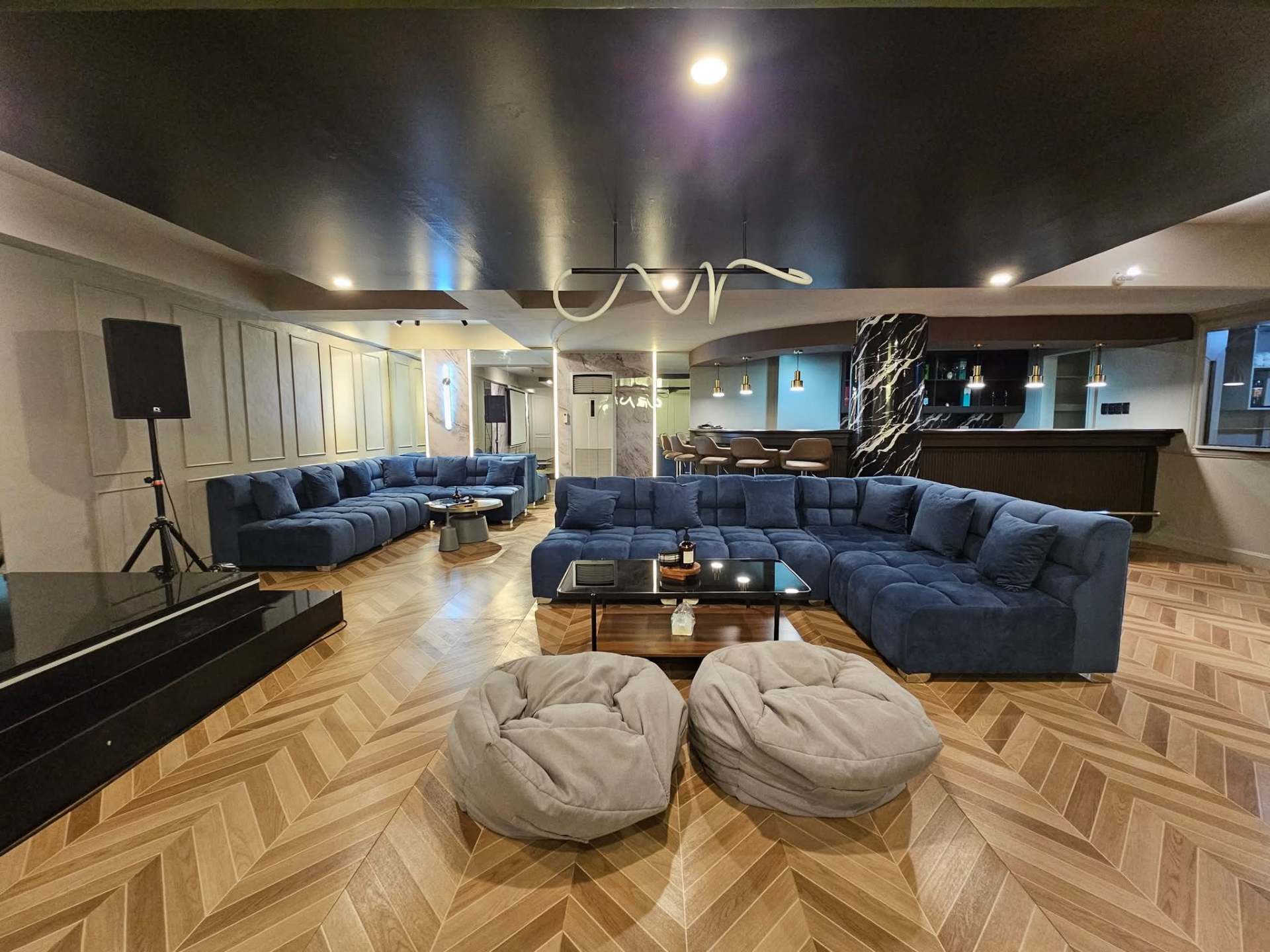 Movie and karaoke lounge with deep blue velvet sectional and stage lighting