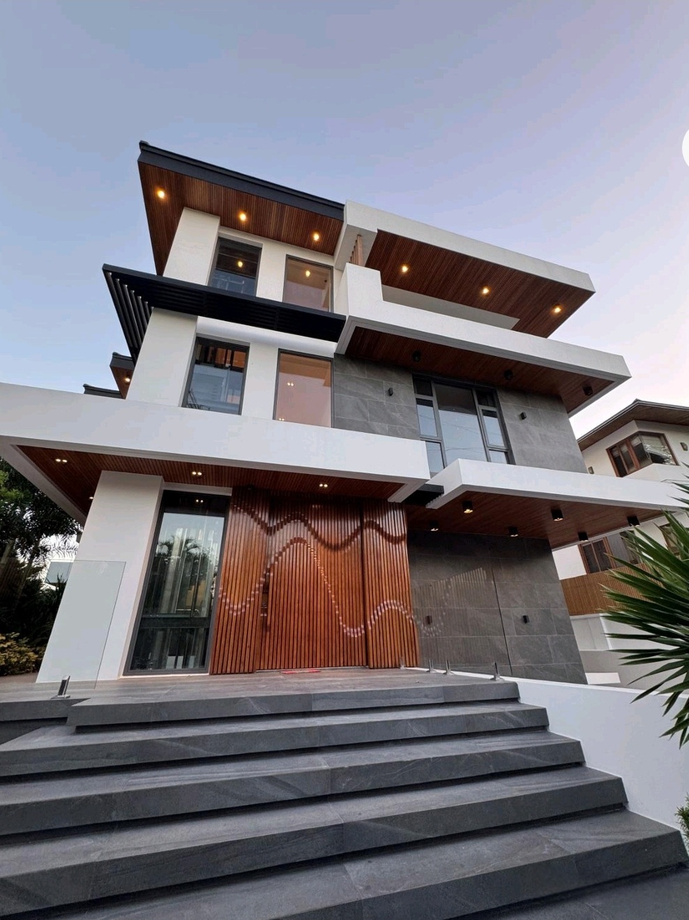 Three-storey modern luxury facade with cantilevered eaves and Narra accents