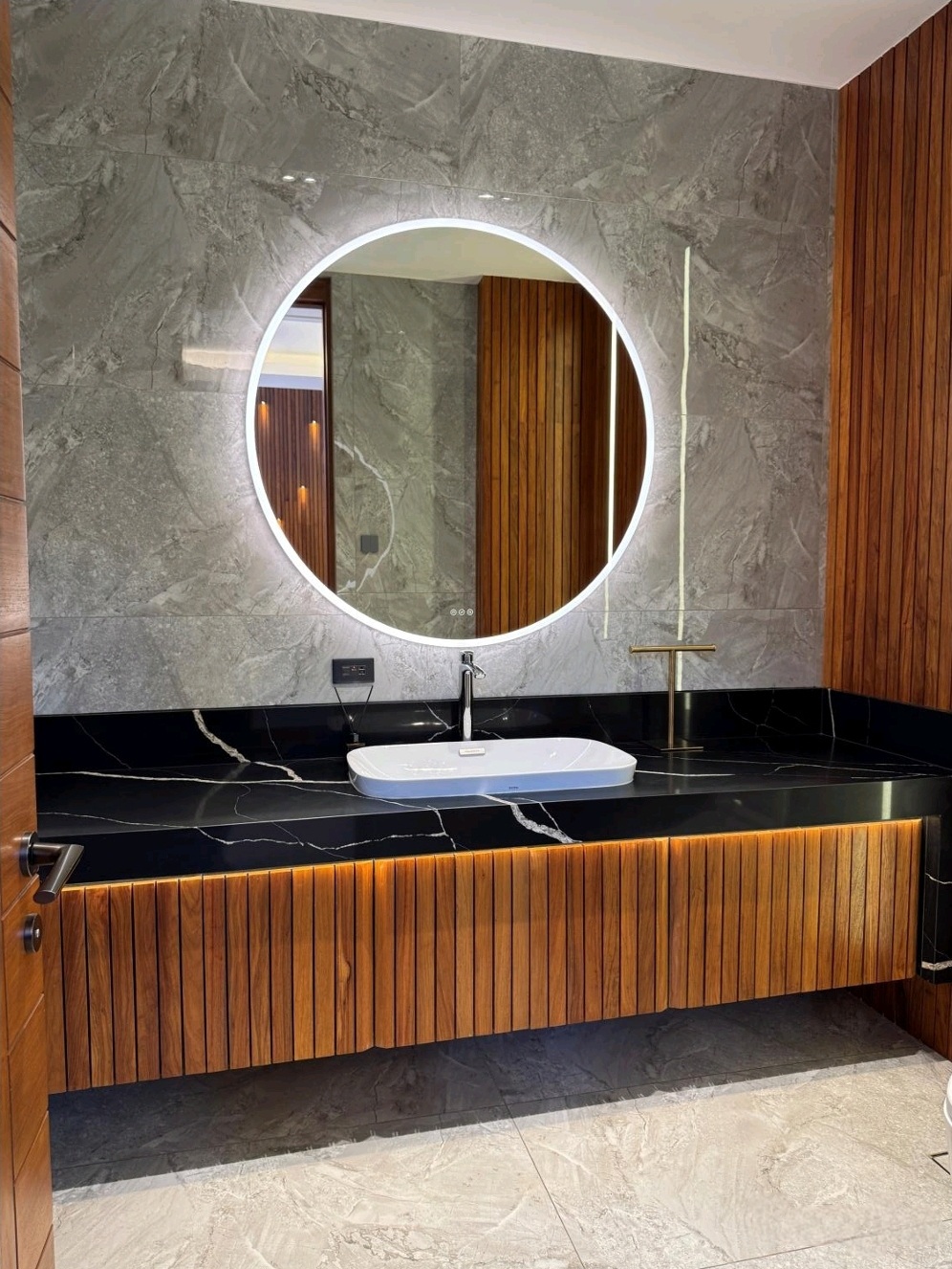 Powder room with marble cladding, Narra vanity and backlit mirror