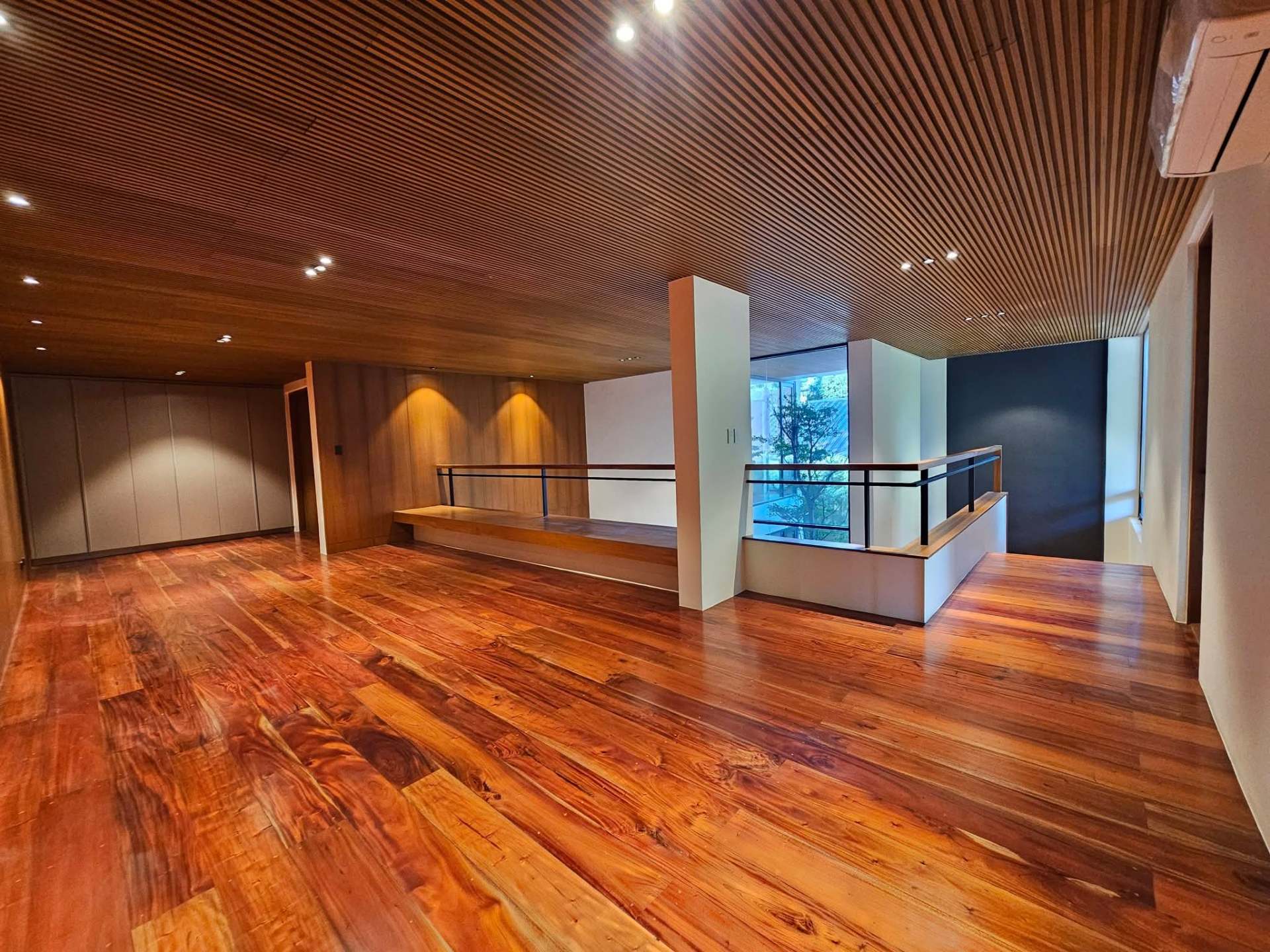 Spacious attic with reddish hardwood floors and integrated cabinetry