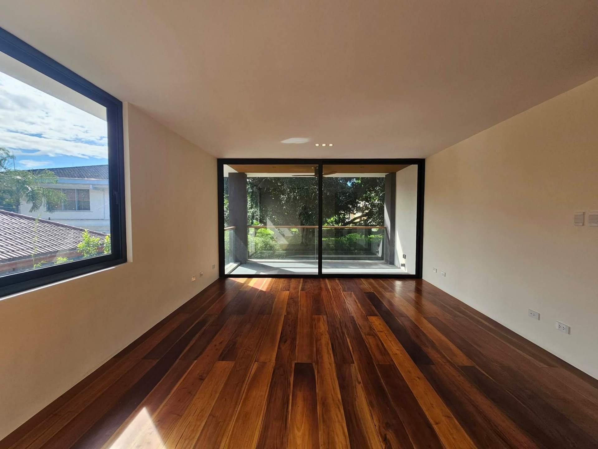 Bedroom with hardwood floors opening to private balcony