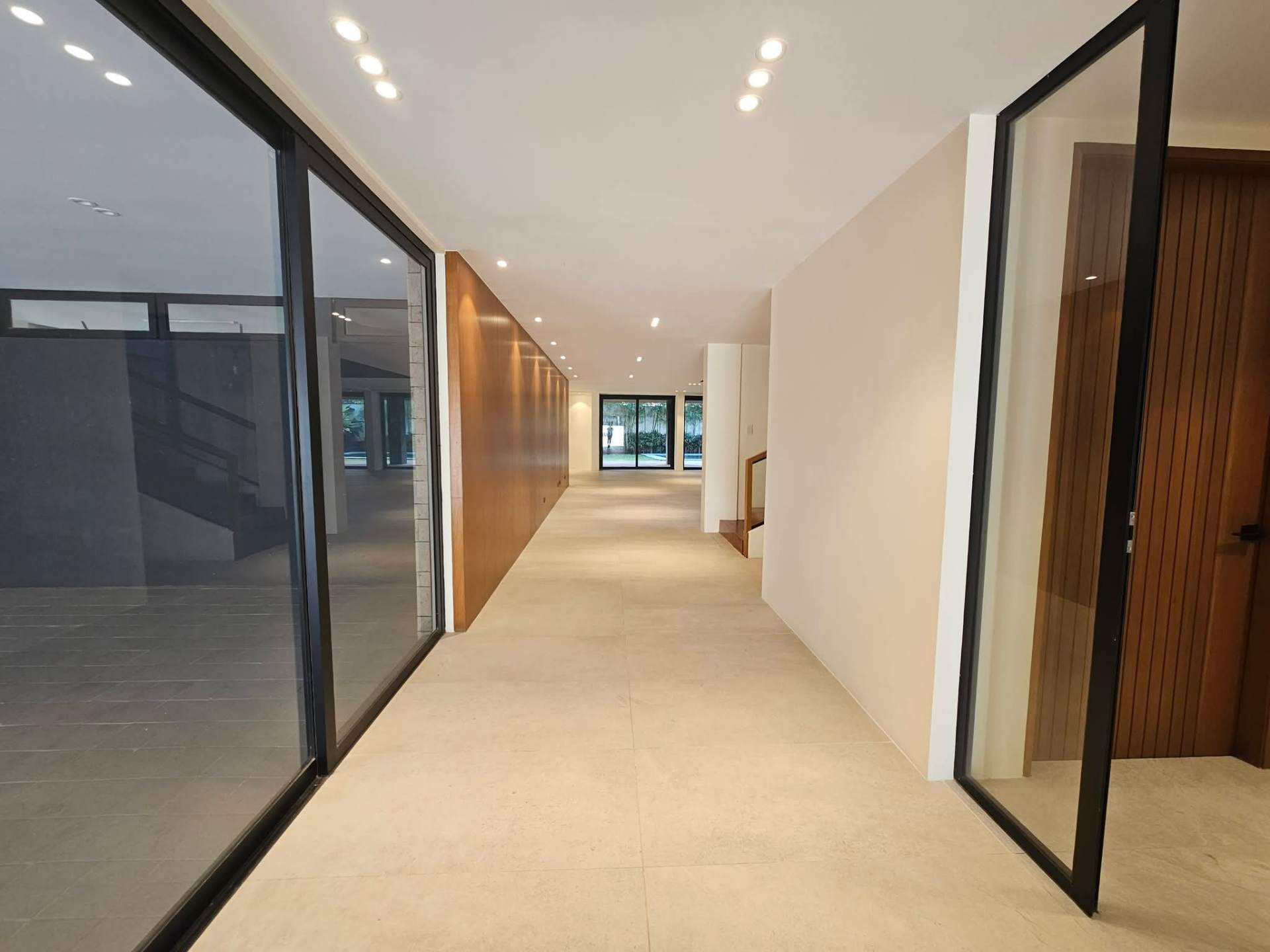 Long ground-floor hallway with stone tiles and timber feature wall