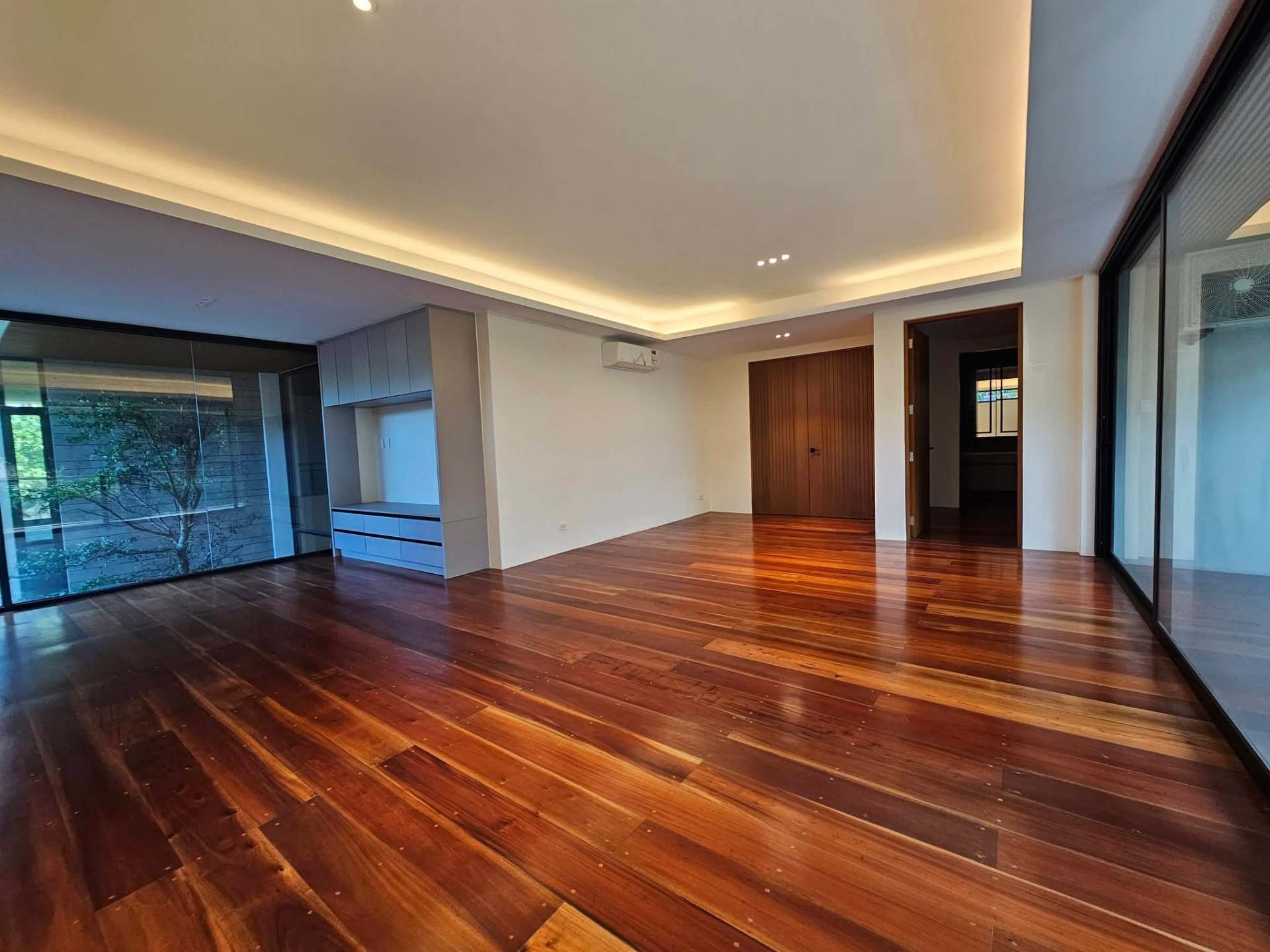 Living area with rich hardwood floors and cove lighting
