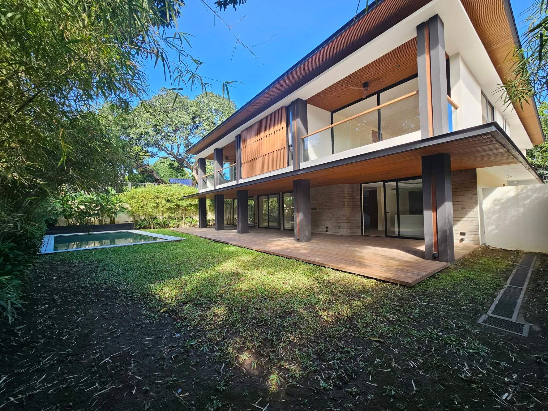 Rear elevation with wood louvers, deck, and pool view