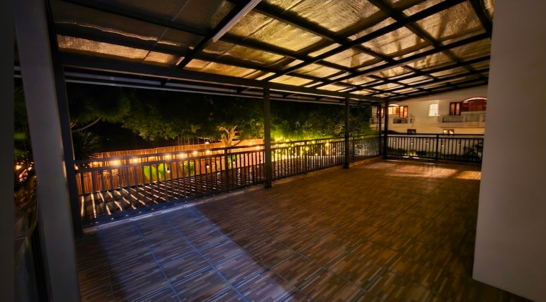 Large covered balcony deck with garden views at night