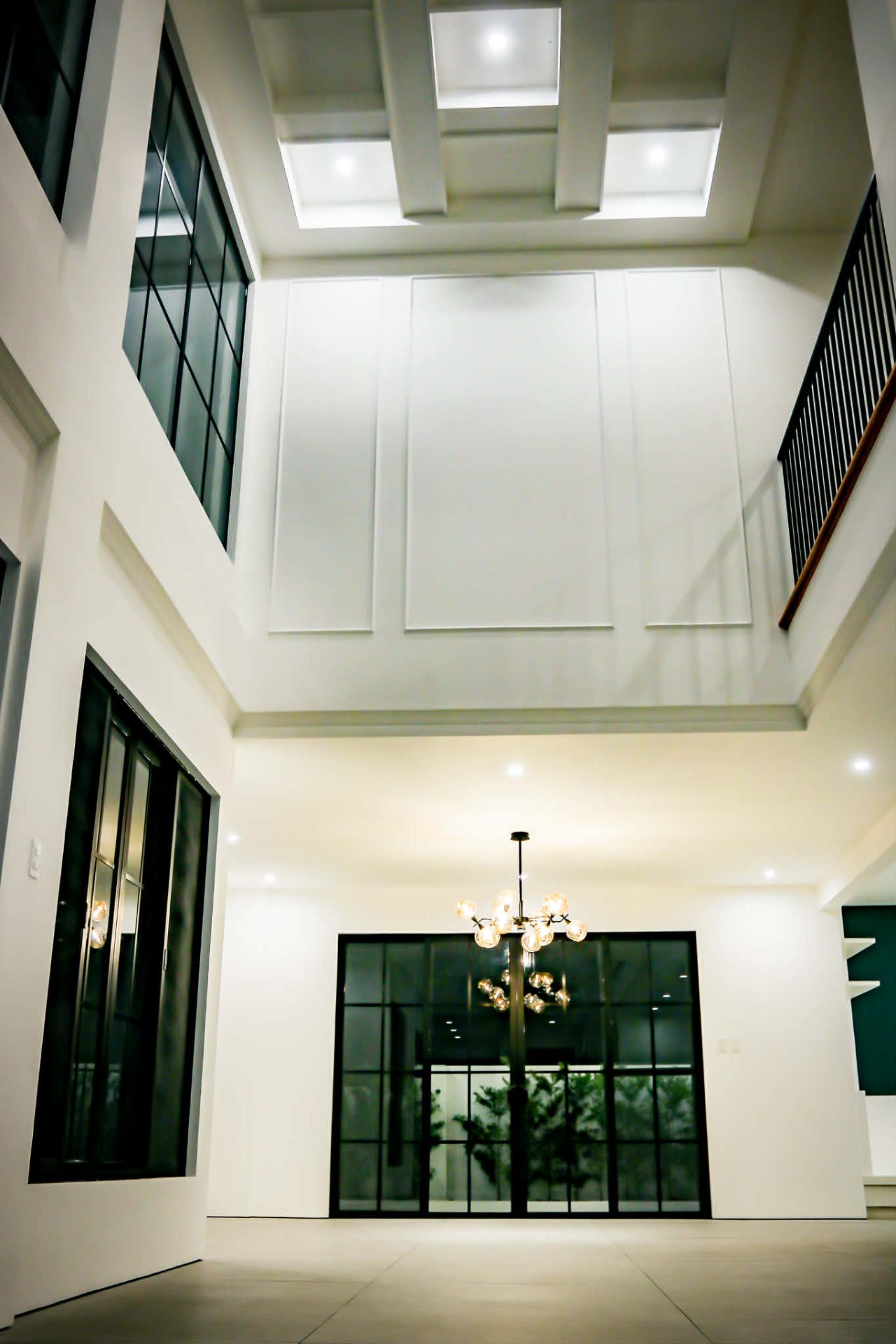 Double-height foyer with coffered ceiling and black-framed casement windows