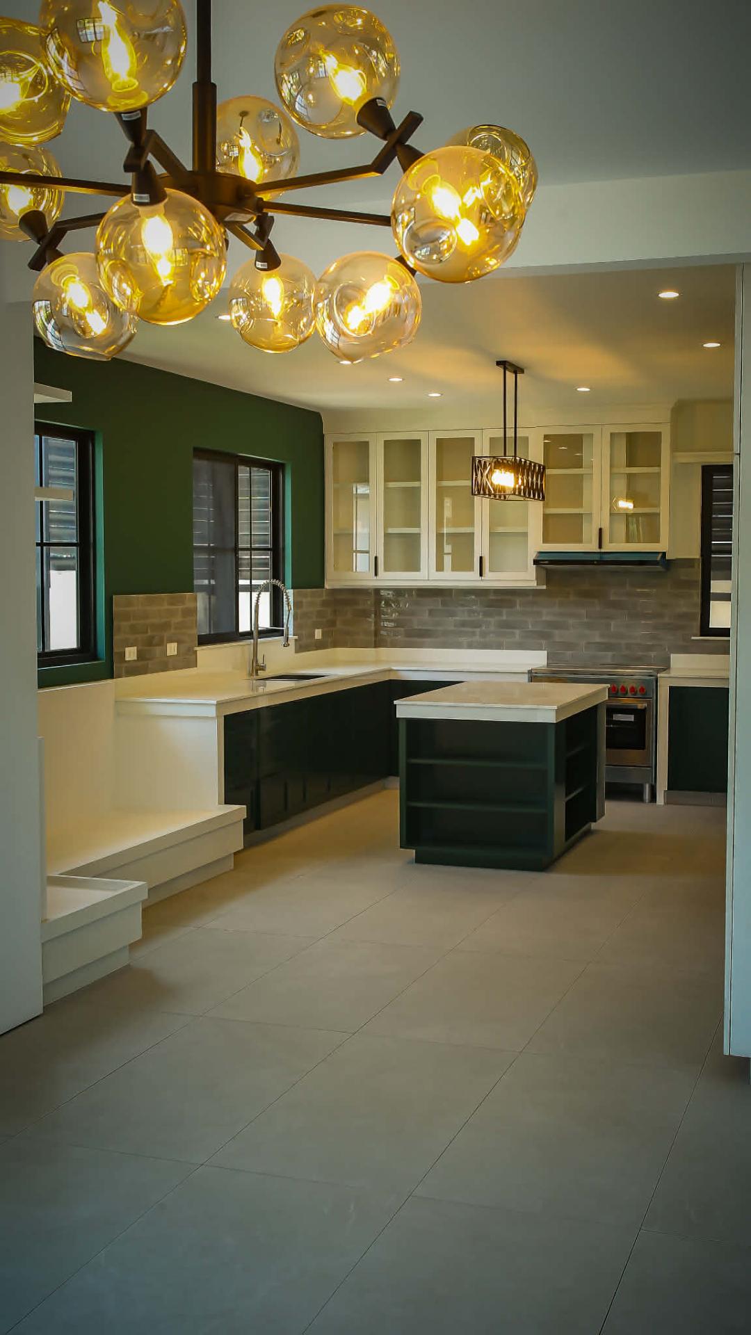 Open kitchen with deep-green cabinetry and amber globe chandelier
