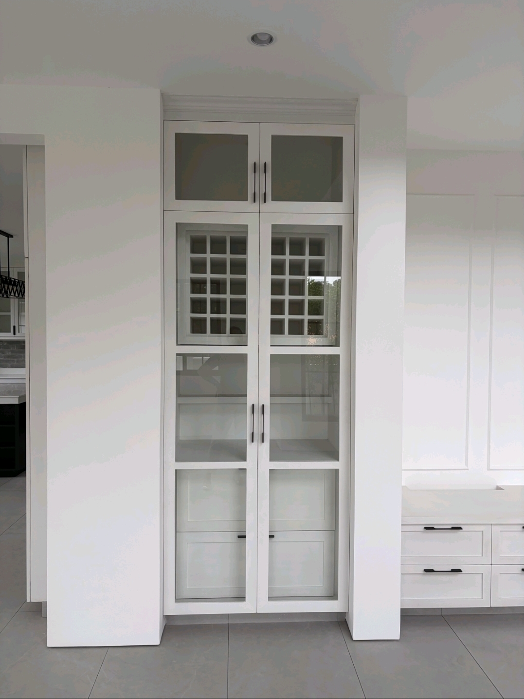 Built-in glass-front pantry cabinetry with shaker doors and matte-black hardware