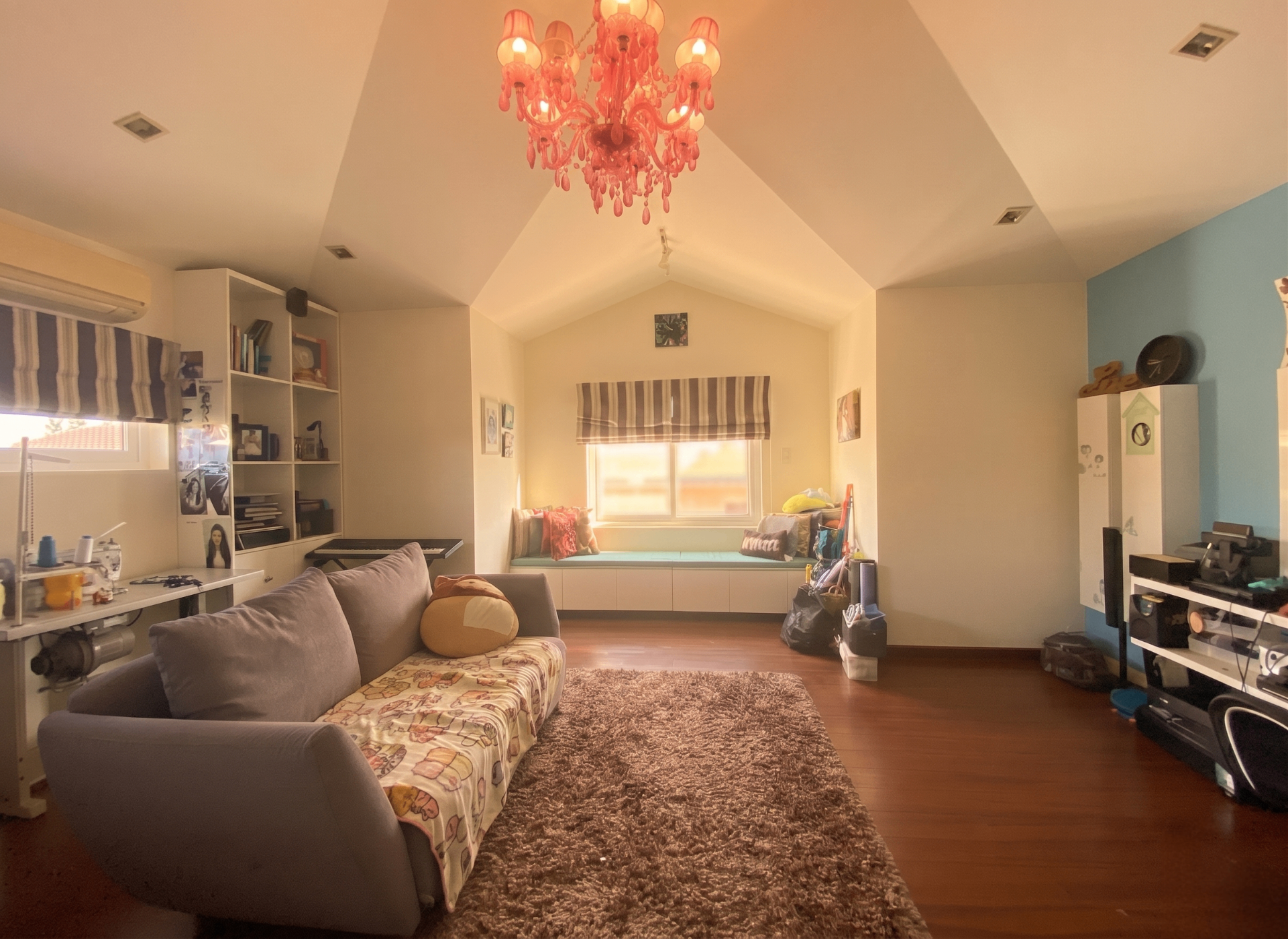 Attic-level family entertainment hall with vaulted ceiling, window-seat nook and statement chandelier