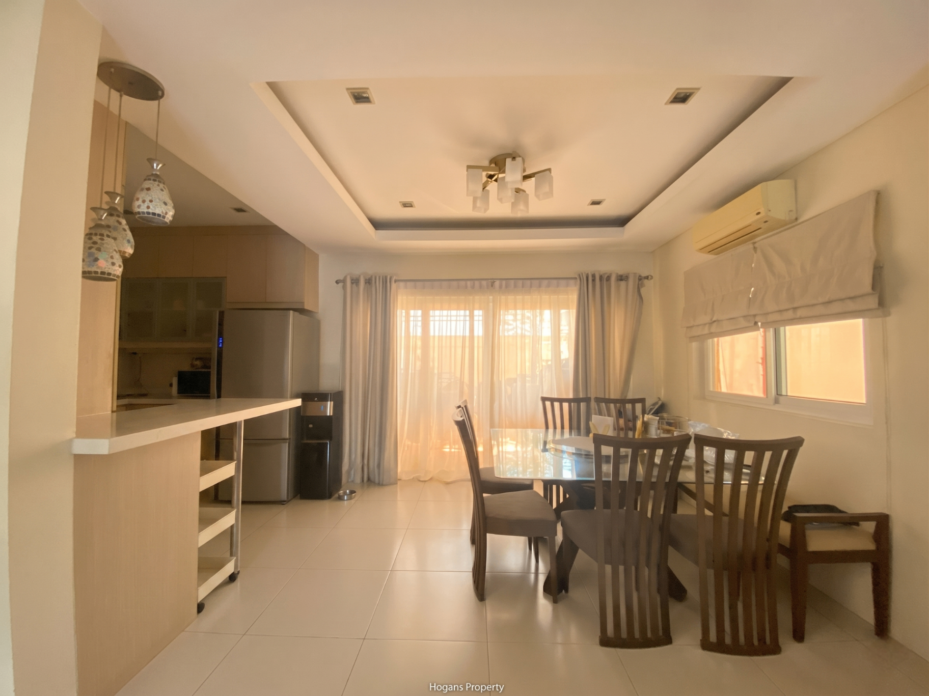 Dining area opening to the lanai with mosaic pendant lights and breakfast counter to the kitchen