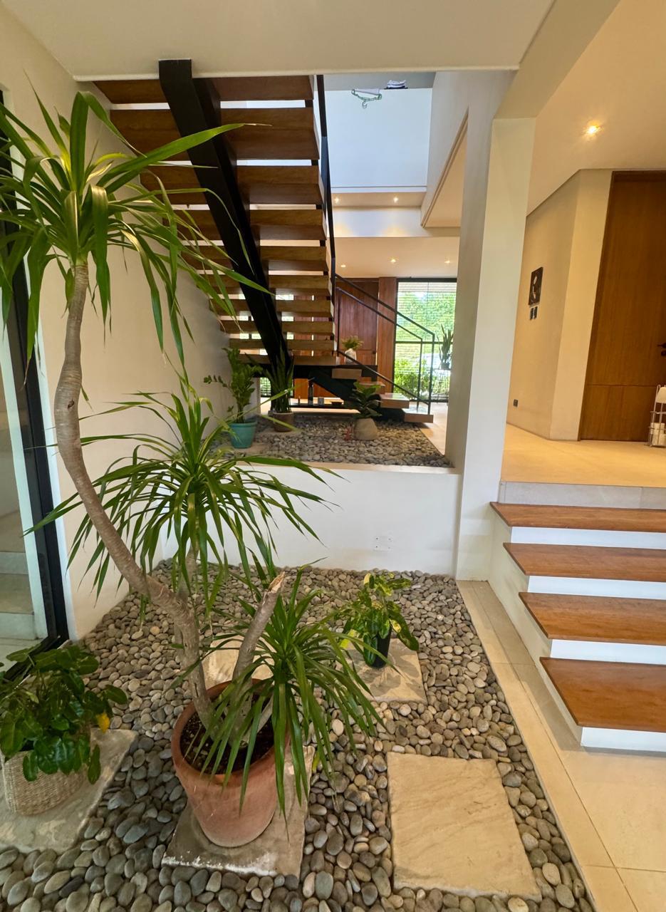 Garden atrium with pebble landscaping and tropical greenery beneath the open stair