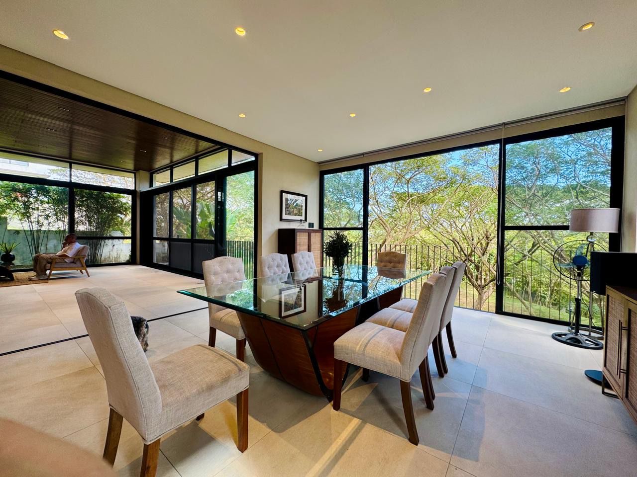 Open dining and lanai with sliding glass walls overlooking the tree canopy