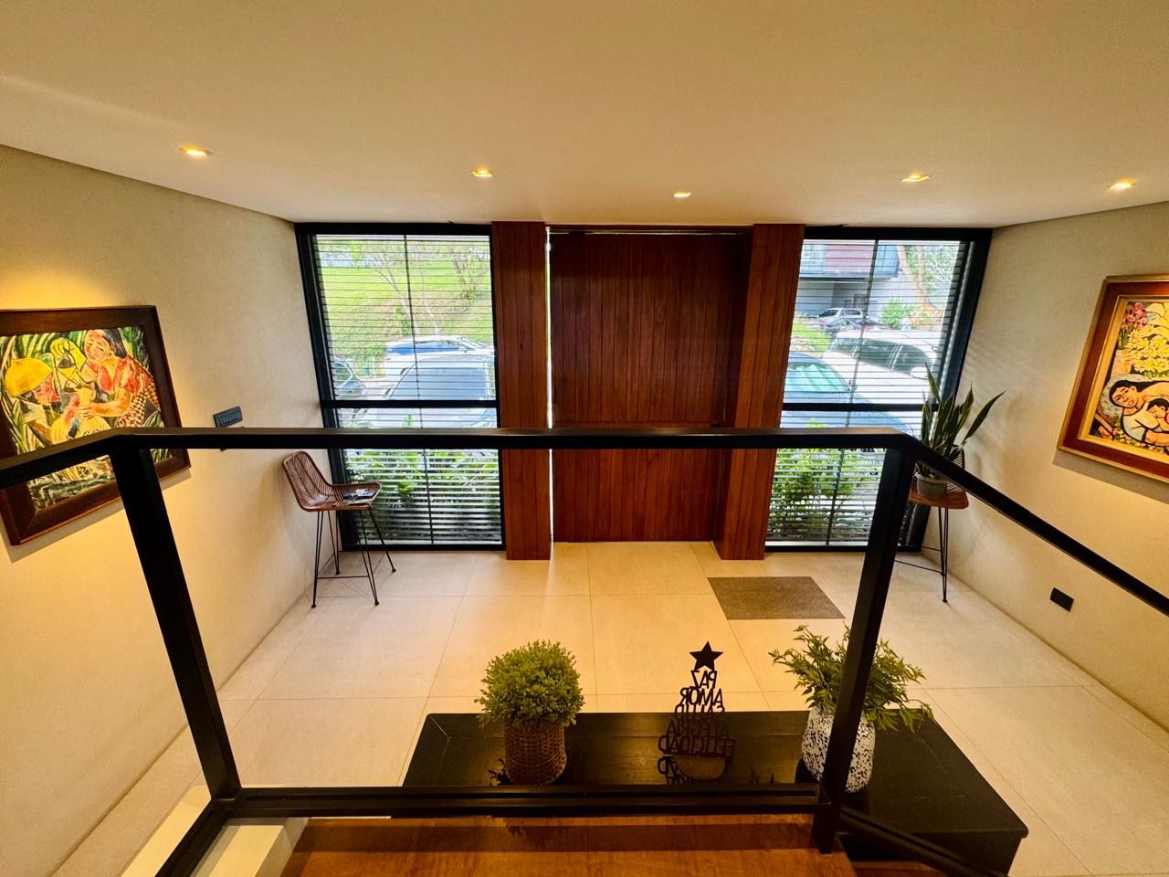 Double-volume foyer viewed from the mezzanine, with wood-clad entry and curated art