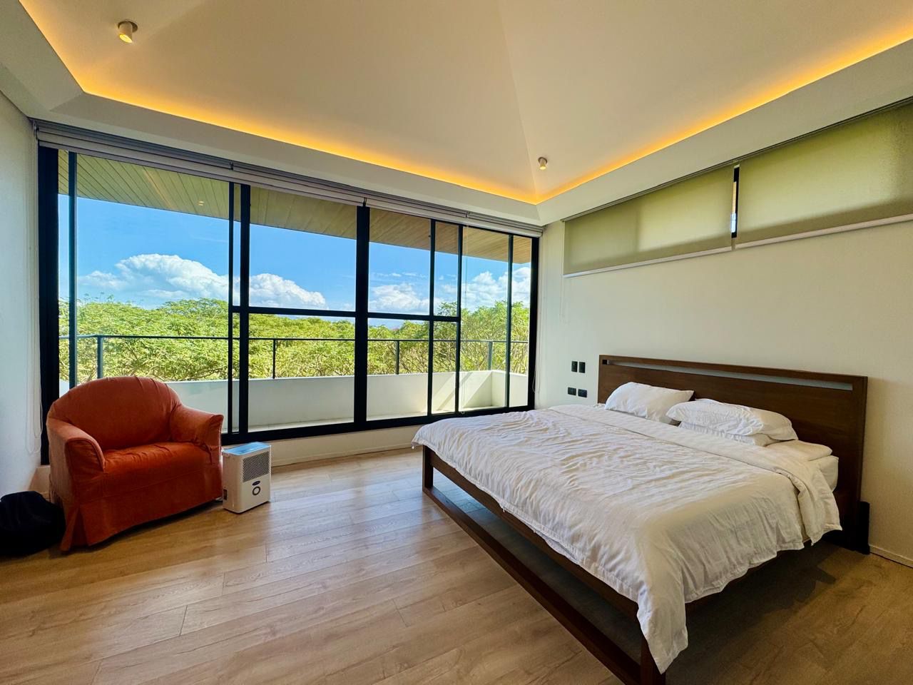 Master bedroom with king bed, wood floors, cove lighting and floor-to-ceiling balcony glazing