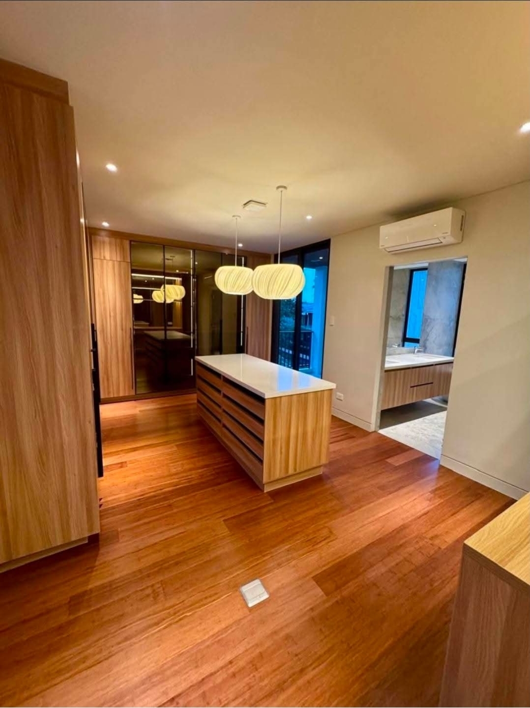 Walk-in closet with custom millwork, dressing island, and en-suite bath beyond